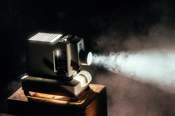 A vintage projector casting a beam of light in a dark room.