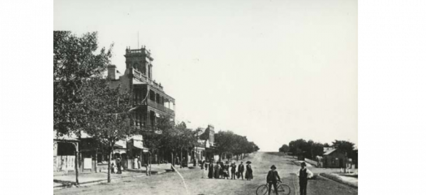 A black-and-white historical photograph of a street and waterfront.