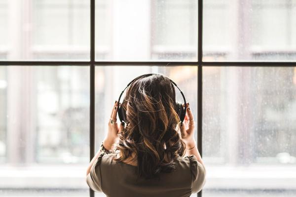 A person wearing headphones beside a window.