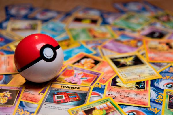 A red-and-white Poké Ball resting on a spread of Pokémon cards.