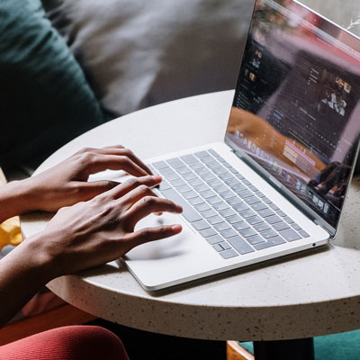 Hands typing on a laptop resting on a small table.
