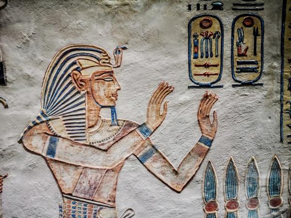 An ancient Egyptian figure and hieroglyphs painted on a wall.